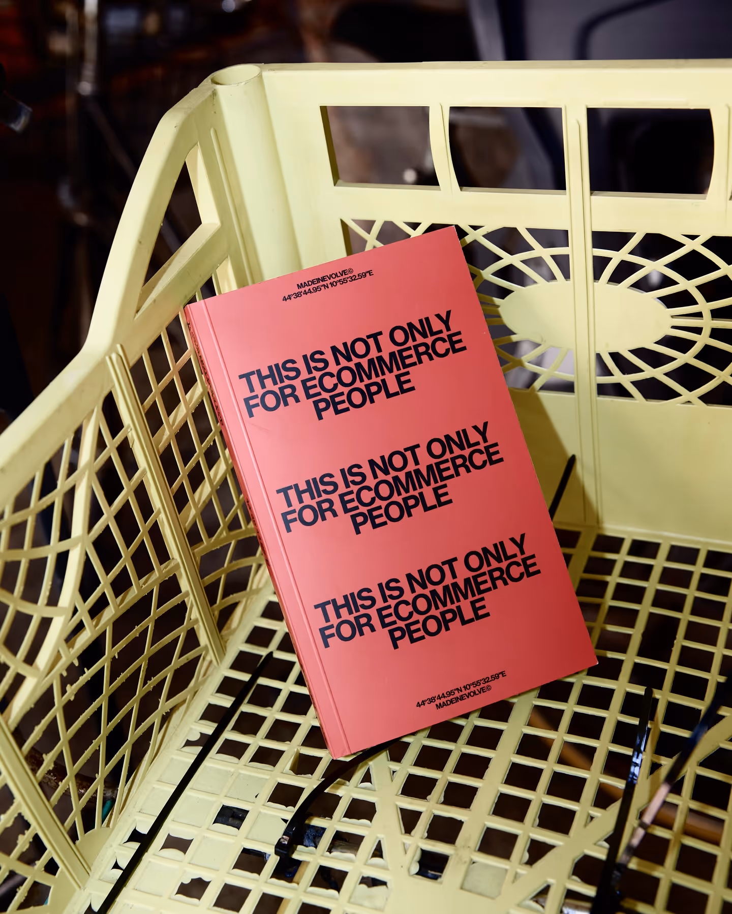 Red book with black text 'This is not only for ecommerce people' repeated three times, placed on a yellow lattice chair.