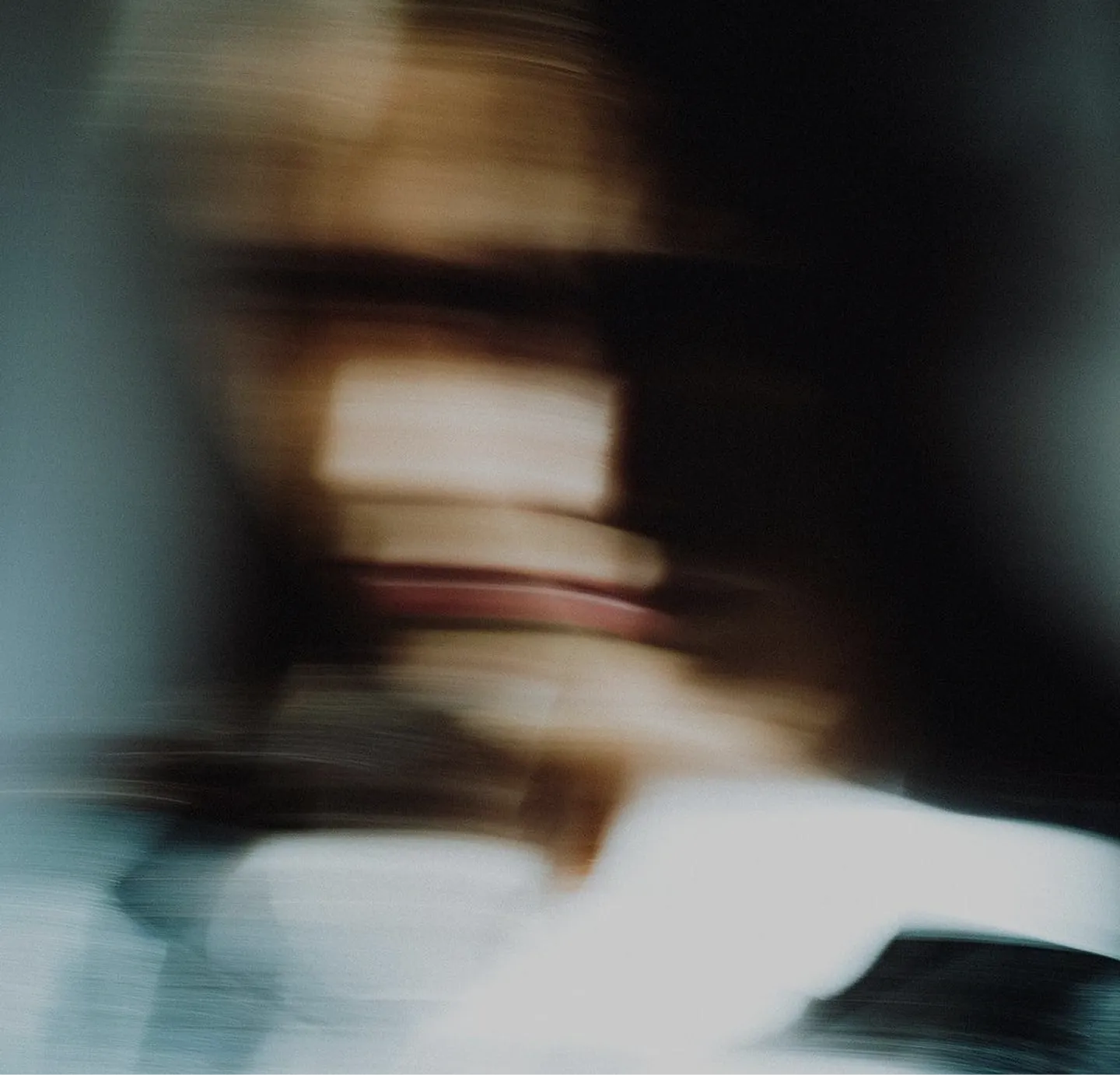 Blurred motion image of a person with indistinct facial features and dark hair.
